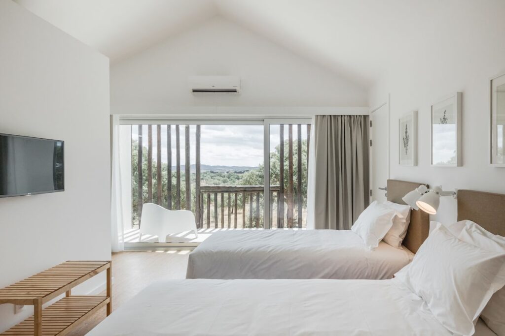 Quarto minimalista com portas de correr de vidro e terraço suspenso no Sobreiras Alentejo, calma na lua de mel na europa.