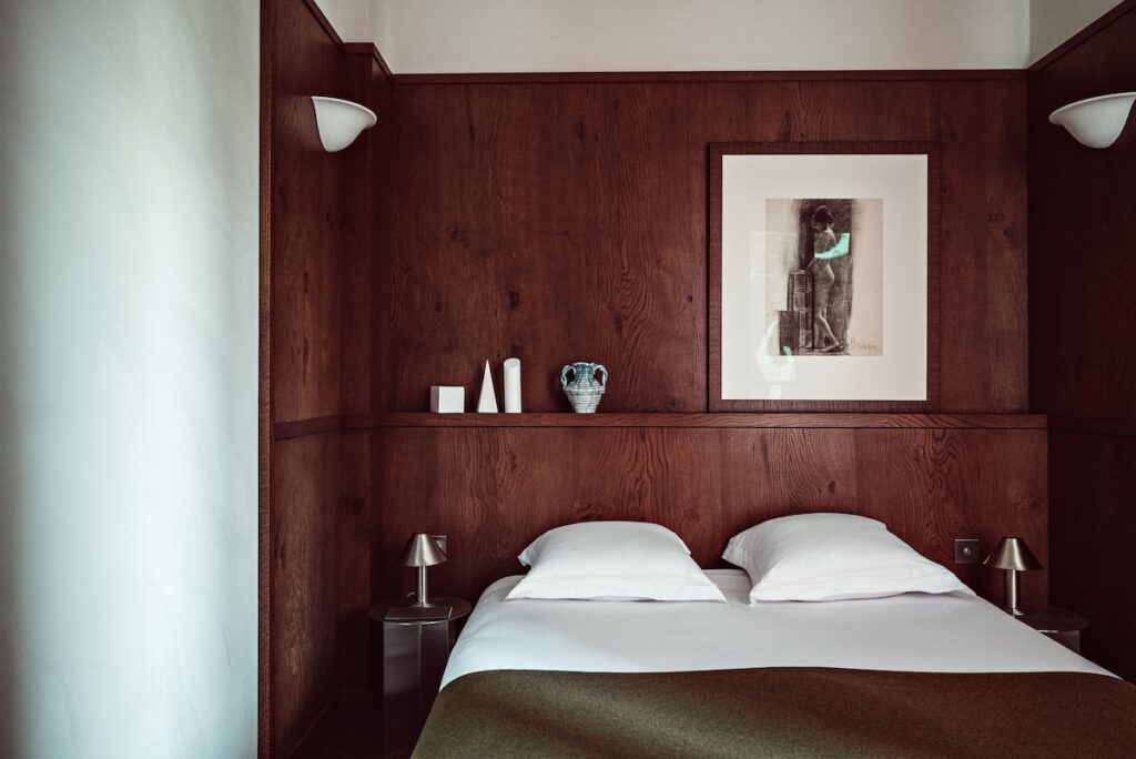 Quarto com painel de madeira no Hôtel des Académies et des Arts, um dos requintados hoteis boutique em paris com design de interiores intimista e artístico.