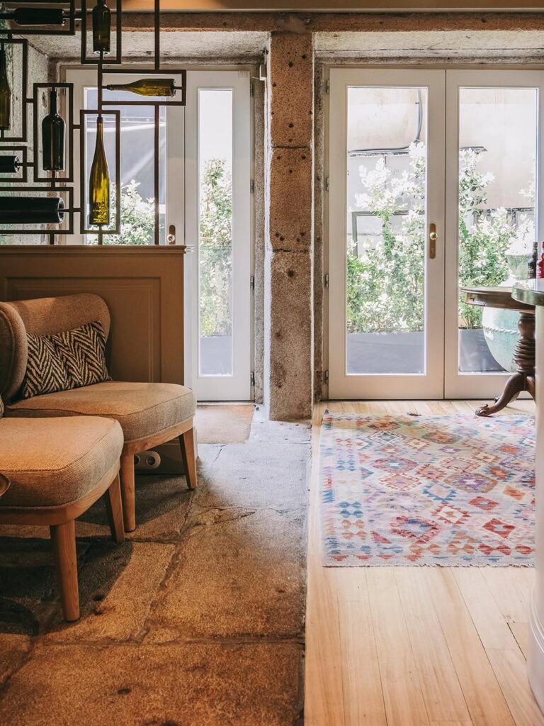 Lobby acolhedor com paredes de pedra exposta e piso de madeira no Gran Cruz House, ótima opção de hotel boutique no Porto.