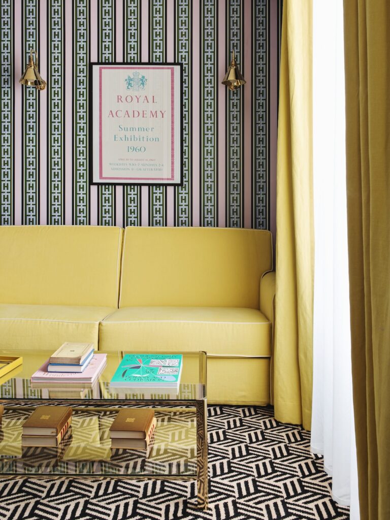Sala de estar com sofá amarelo e papel de parede listrado rosa e verde no Hôtel Les Deux Gares, destaque entre os hoteis boutique em paris.
