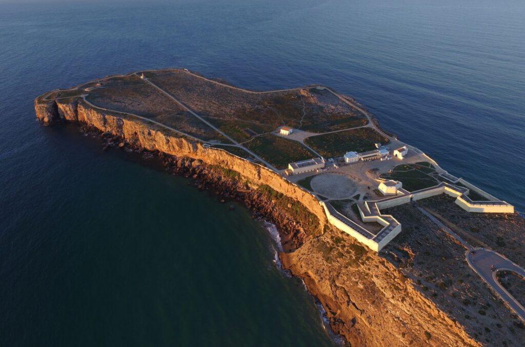 Penhascos iluminados da Fortaleza de Sagres, na Costa Vicentina, durante o pôr do sol na melhor época para visitar portugal.