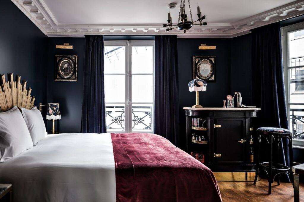 Decoração elegante no Hôtel Providence -Canal Saint -Martin, referência de hoteis boutique em paris, com paredes escuras e cabeceira de sol dourada.