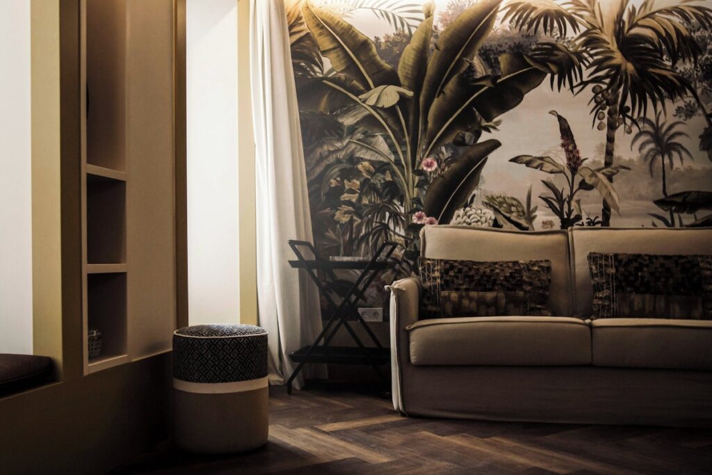Sala de estar no The Ivens Hotel com papel de parede de floresta tropical e sofá de linho, charme autêntico nos hoteis boutique em lisboa.