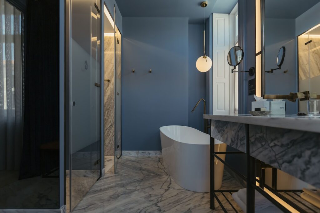 Banheiro luxuoso com paredes azul-ardósia e banheira de imersão no Torel Avantgarde. Descubra se hotel boutique vale a pena.