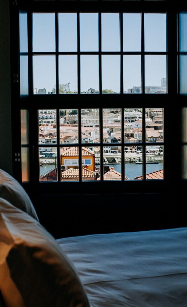 Vista para o Rio Douro enquadrada por janela clássica em hotel boutique no Porto, com telhados tradicionais e fachadas históricas ao fundo sob a luz do dia.