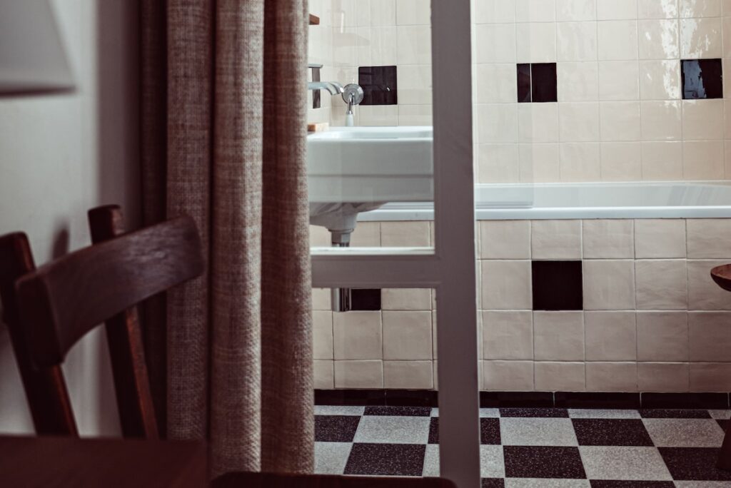 Banheiro com piso xadrez e azulejos creme no Hôtel des Académies et des Arts, um dos charmosos hoteis boutique em paris com design retrô e contemporâneo.