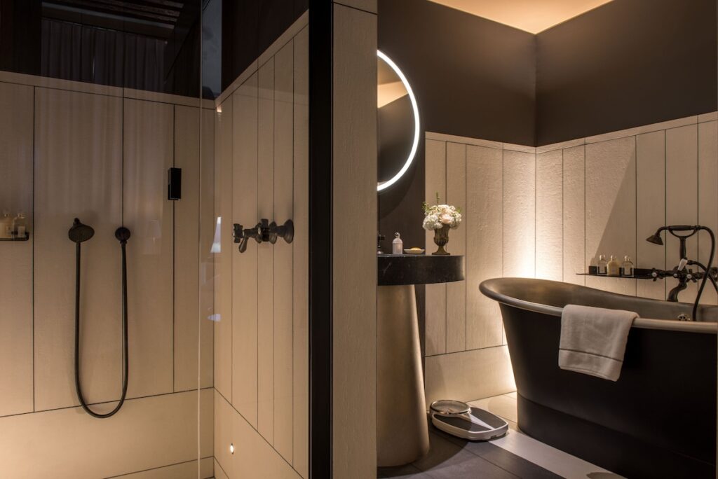 Banheiro de luxo com banheira vitoriana preta e metais retrô no Cour des Vosges, destaque entre hoteis boutique em paris.
