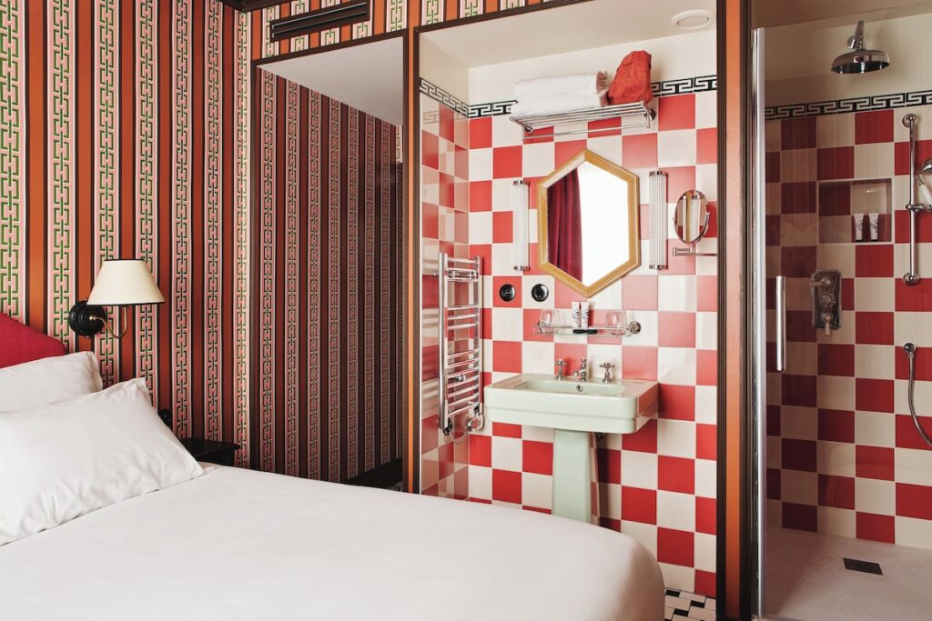Quarto com banheiro integrado revestido em azulejos vermelhos e brancos no Hôtel Les Deux Gares, charmoso hotel boutique em paris.