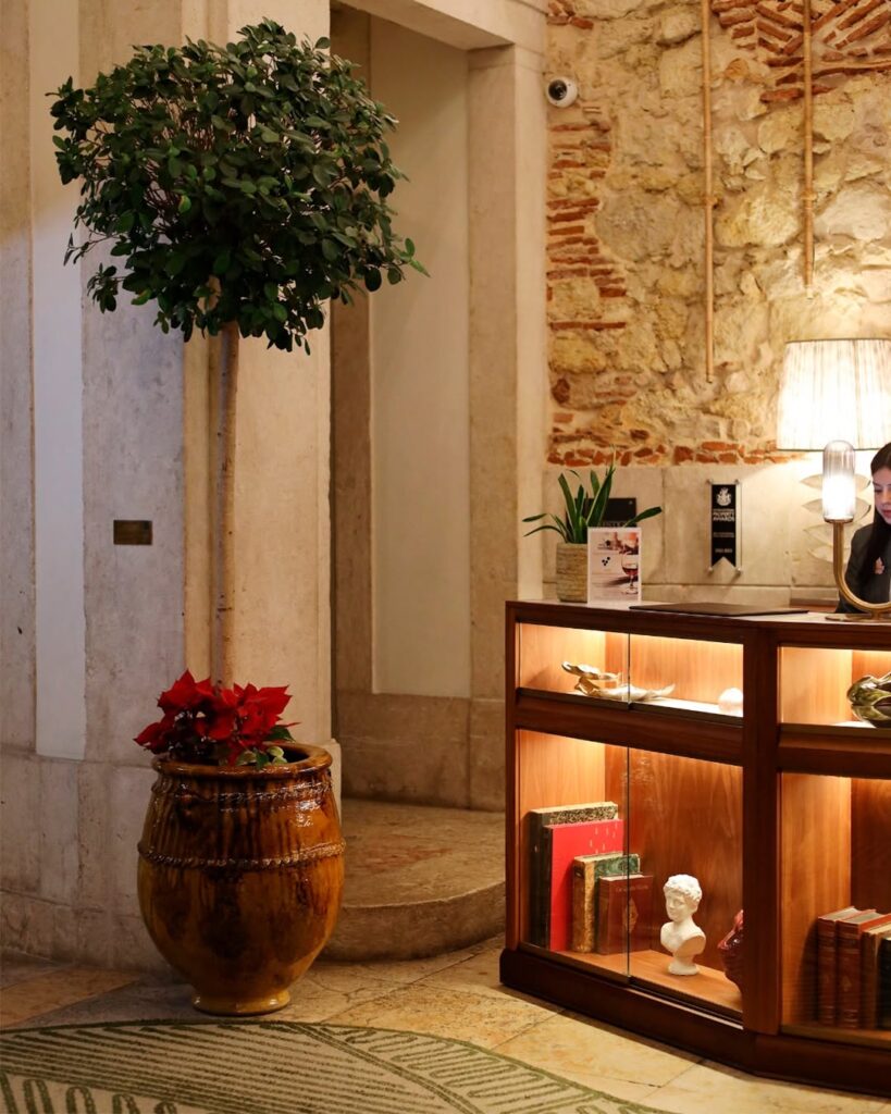 Lobby com parede de pedra e balcão de madeira no Ludovice Wine Experience, um dos sofisticados hoteis boutique em lisboa.