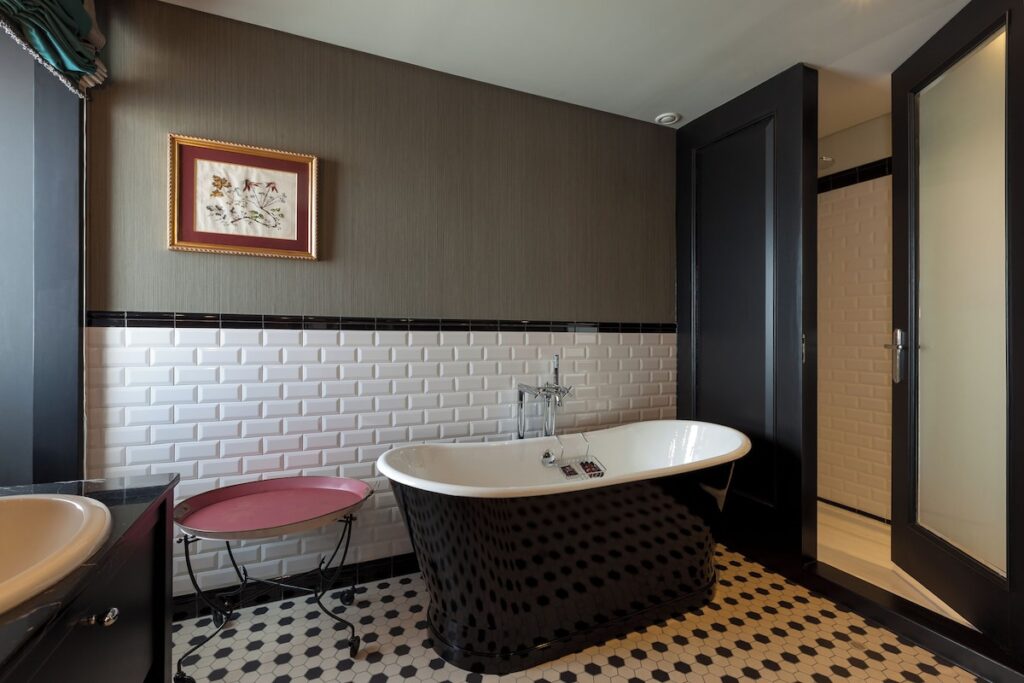 Banheiro retrô no Valverde Hotel com banheira preta de imersão, pastilhas hexagonais e subway tiles, destaque de hoteis boutique em lisboa.