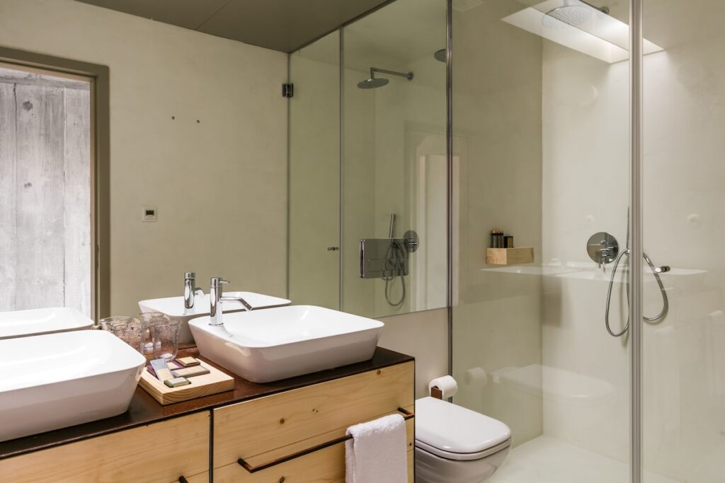 Banheiro moderno com bancada de madeira e cubas duplas na cobertura de um dos hotéis de charme no Porto. Foto do Armazém Luxury Housing.