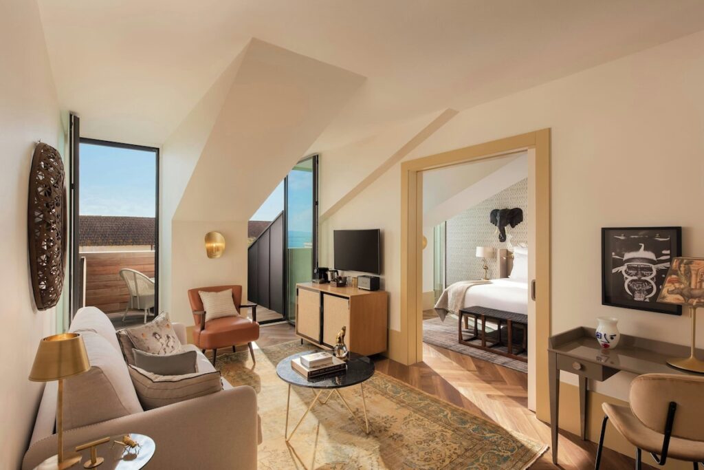 Suíte de ático no The Ivens Hotel com tetos inclinados, sala de estar decorada e quarto integrado, ícone dos hoteis boutique em lisboa.