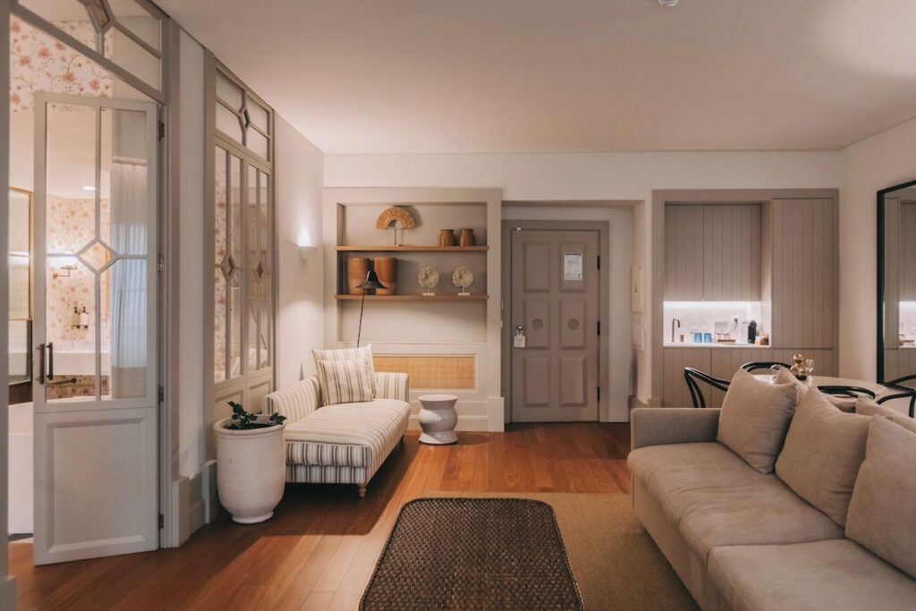 Suíte integrada com sofá, chaise listrada e divisória de vidro para o banheiro no Torel Saboaria, um dos charmosos hotéis de charme no Porto.
