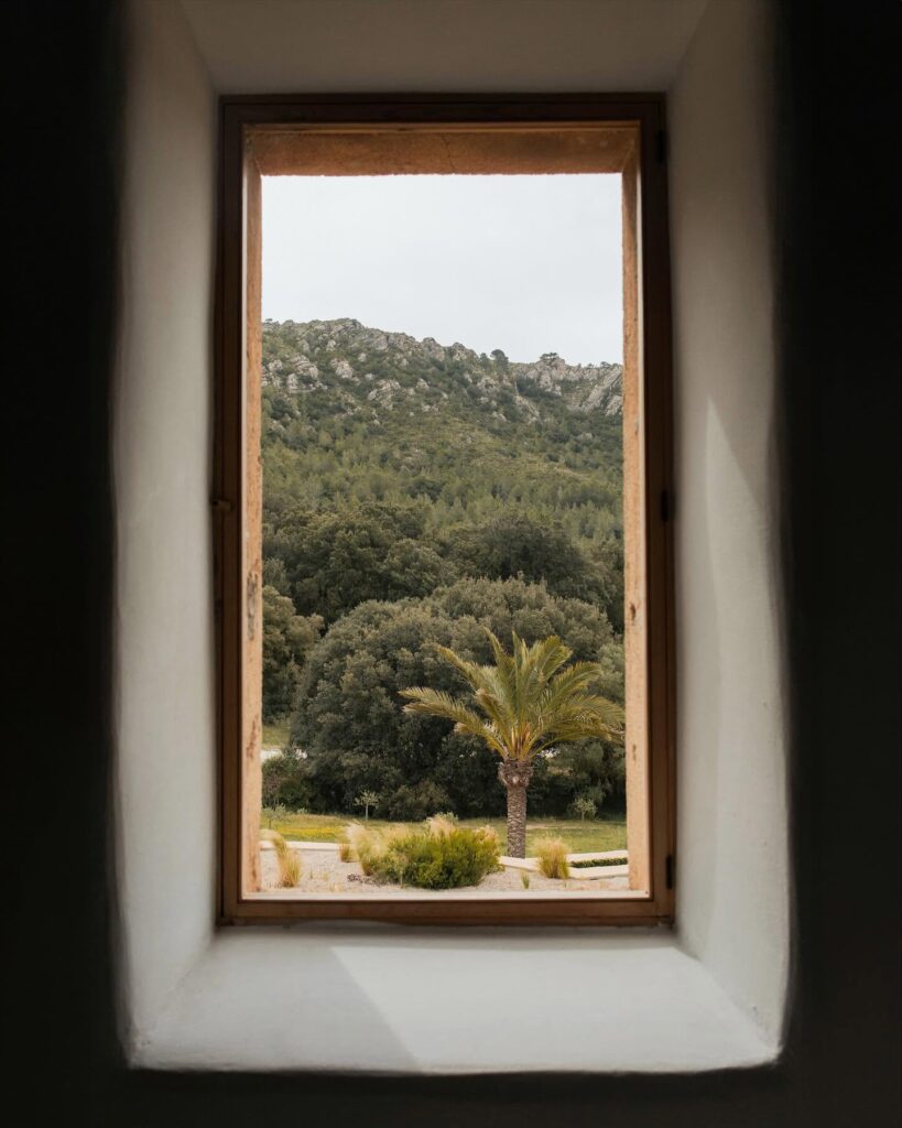 Vista de janela com moldura de madeira e colinas de Mallorca no Es Racó d'Artà, refúgio de lua de mel na europa.