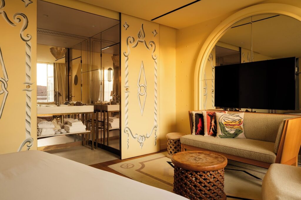 Suíte junior do 9Hotel Confidential com portas decoradas e banheiro espelhado integrado, reforçando o luxo dos hoteis boutique em paris.