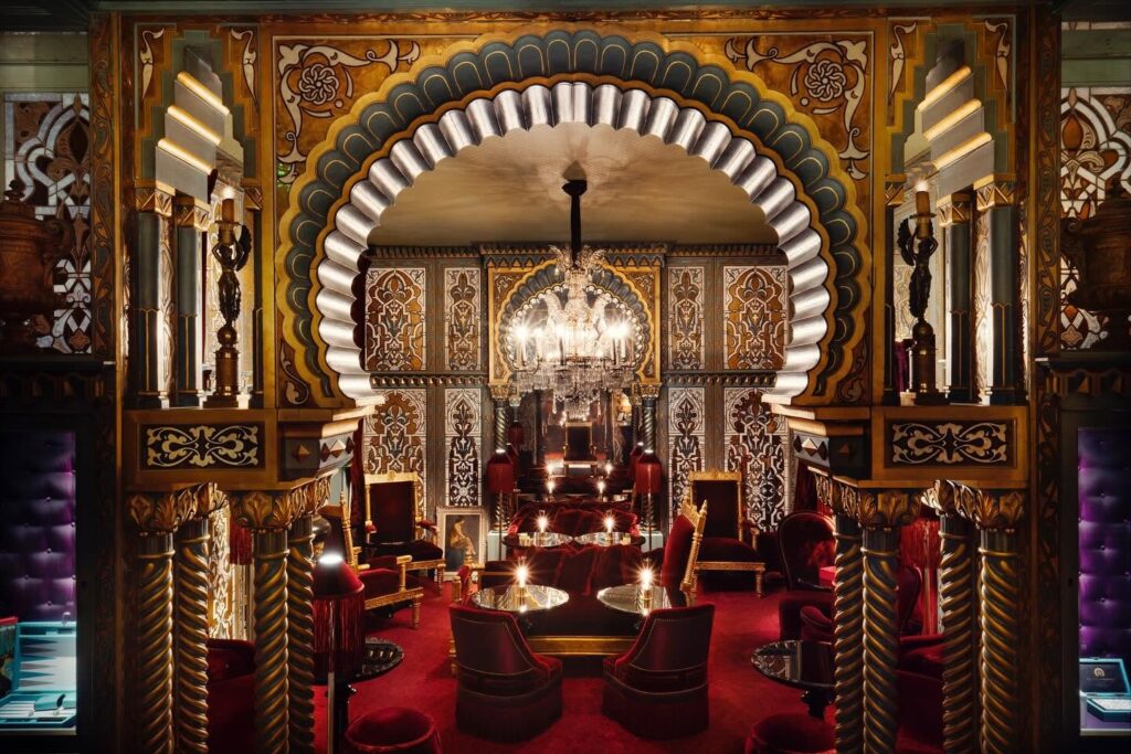 Salão mourisco da Maison Souquet, referência entre os hoteis boutique em paris, com arco decorado, veludo vermelho e lustre de cristal.