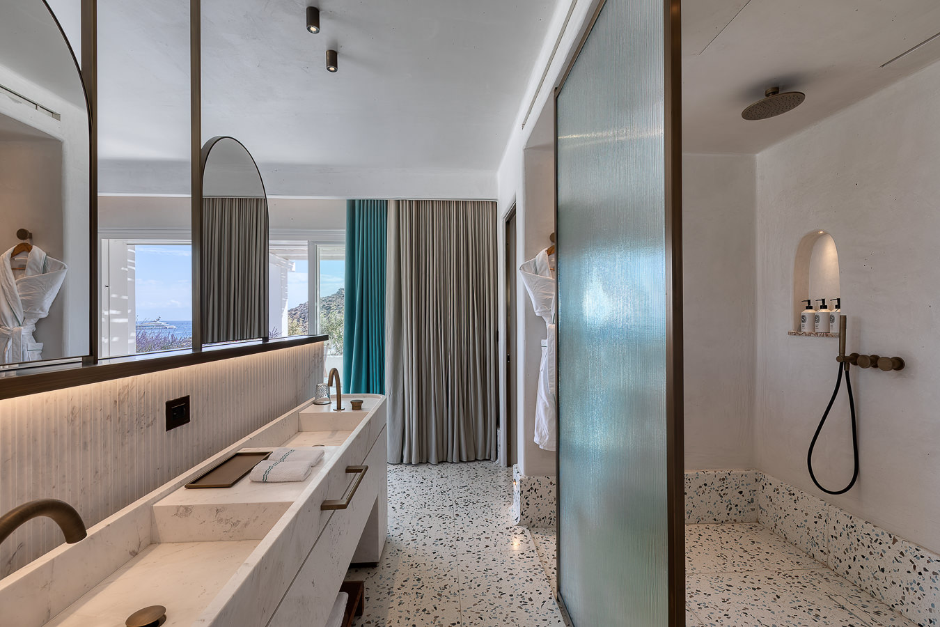 Oliveiras em vasos de barro em pátio interno caiado no Nammos Hotel, charmoso resort em Mykonos de estilo cicládico.