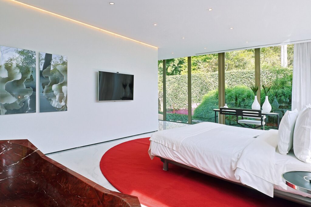 Quarto com tapete circular vermelho e banheira no unique garden de Mairiporã, destaque de hoteis romanticos em são paulo.