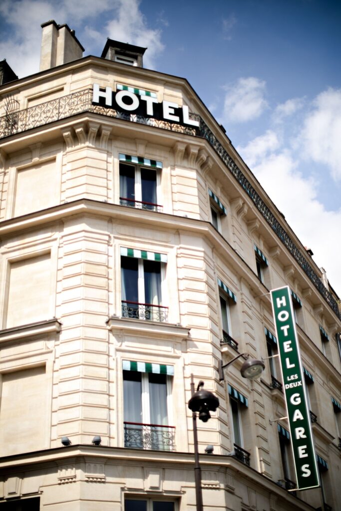 Fachada histórica em estilo haussmanniano com letreiro verde do Hôtel Les Deux Gares, um clássico entre os hoteis boutique em paris.
