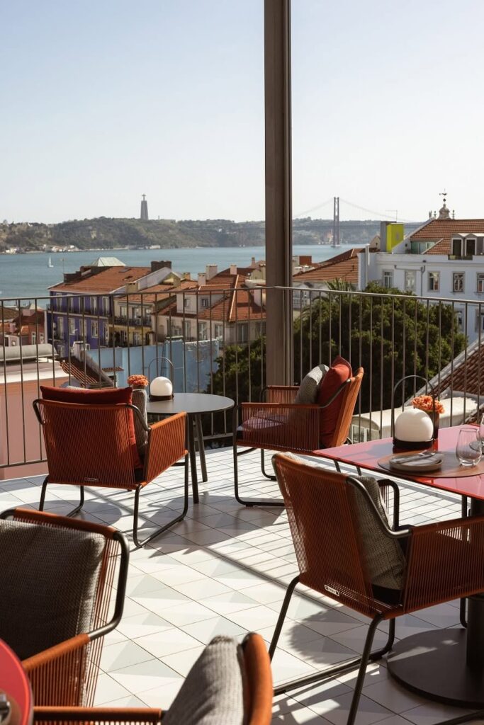 Terraço ao ar livre no Bairro Alto Hotel com vista para o Rio Tejo, mostrando o design das cadeiras terracota deste destaque dos hoteis boutique em lisboa.