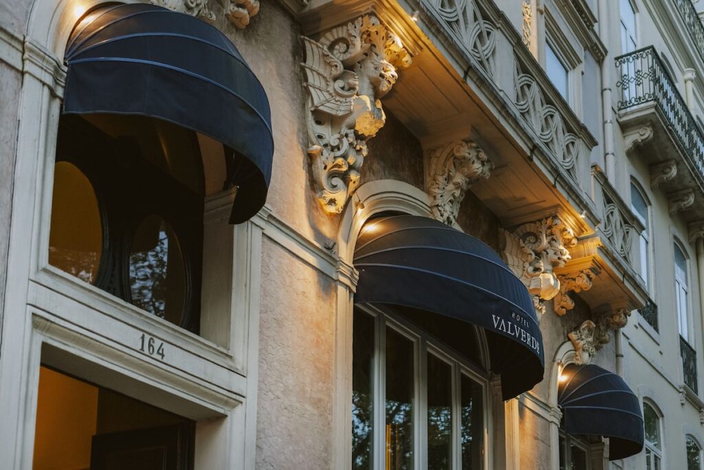 Fachada neoclássica do Valverde Hotel em Lisboa, com mísulas entalhadas e toldos pretos, expoente de design entre os hoteis boutique em lisboa.