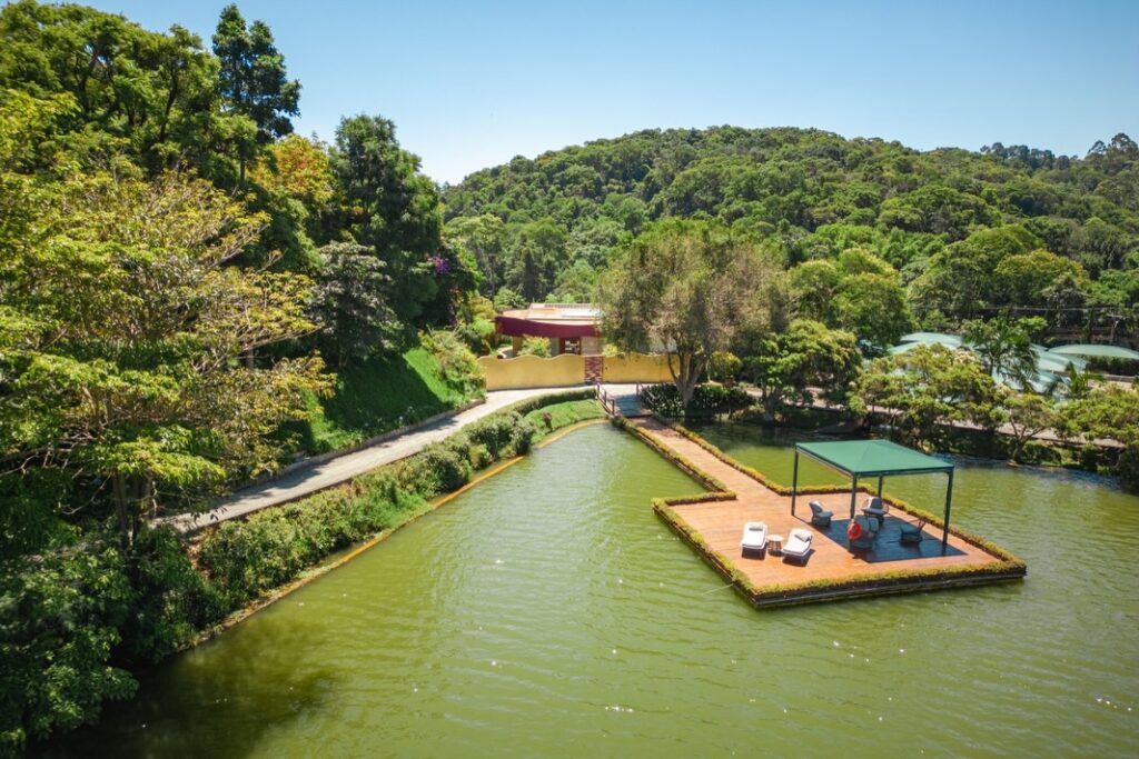 Deck flutuante sobre o lago com vista da Casa de Shiraz no unique garden de Mairiporã, um dos hoteis romanticos em são paulo.