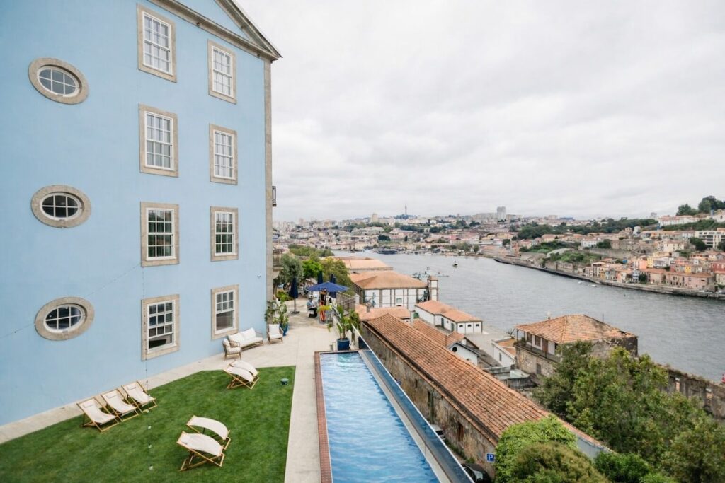Piscina de borda infinita e espreguiçadeiras no gramado de um dos hotéis boutique no Porto com vista para o Rio Douro.