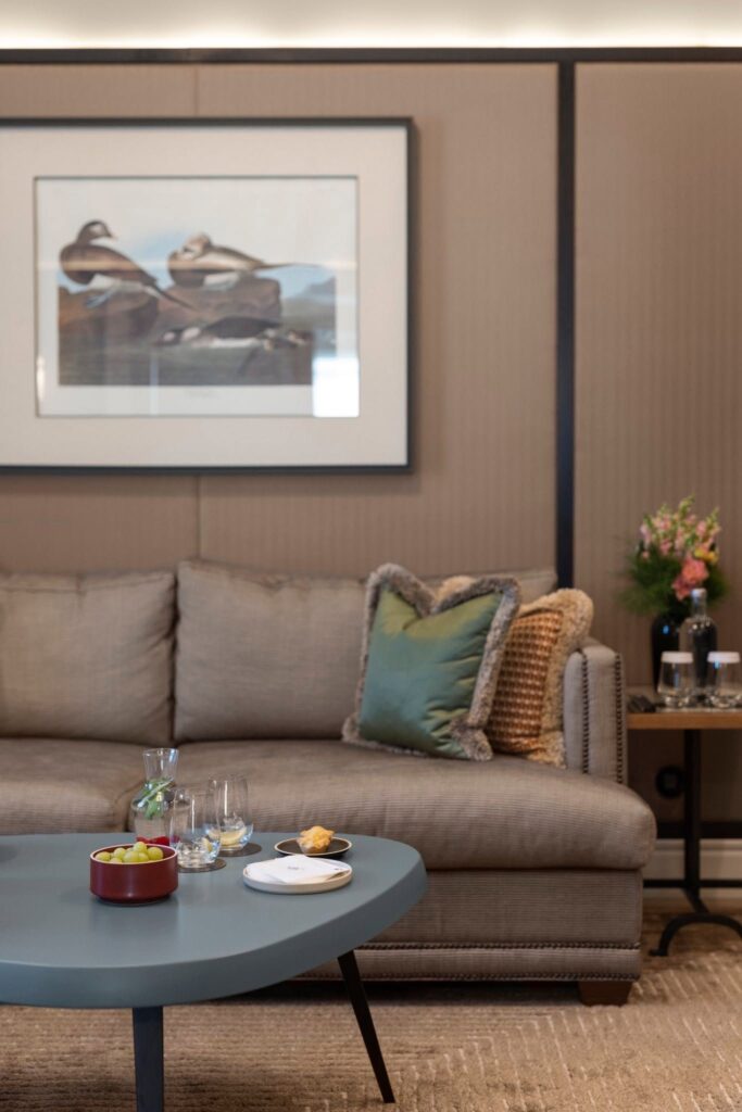 Sala de estar de suíte no Bairro Alto Hotel, excelente opção de hoteis boutique em lisboa, evidenciando detalhes de decoração com sofá cinza e mesa de centro.