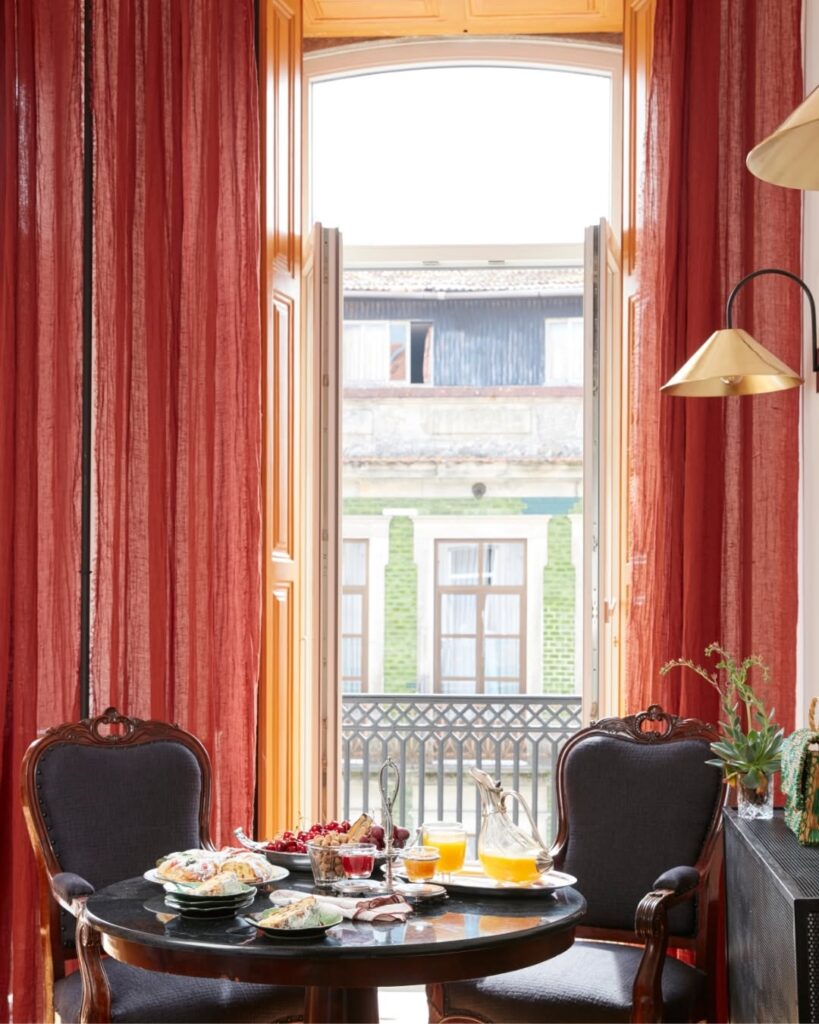 Mesa de café da manhã em quarto clássico no Cocorico Luxury House, uma joia dos hotéis de charme no Porto com design romântico e vista urbana.