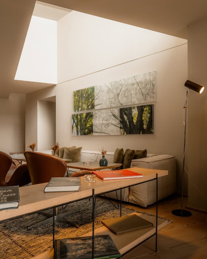 Lobby do Memmo Alfama, expoente dos hoteis boutique em lisboa, iluminado por claraboia, com sofá modular claro e poltrona de couro marrom.
