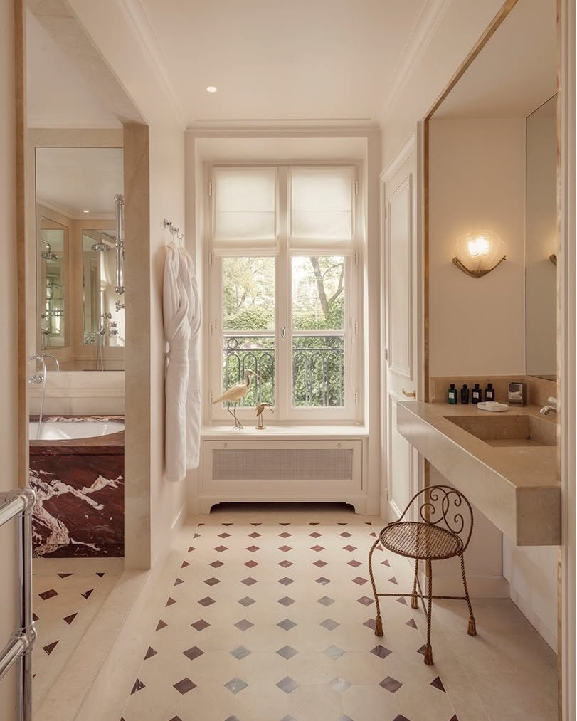 Banheiro clássico com bancada de mármore e área de banheira em mármore vermelho no Hôtel Particulier Montmartre, destaque em hoteis boutique em paris.
