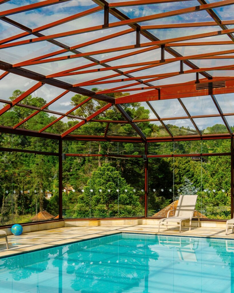 Piscina coberta e aquecida com teto de vidro e vista para a floresta de um dos hotéis românticos em são paulo.