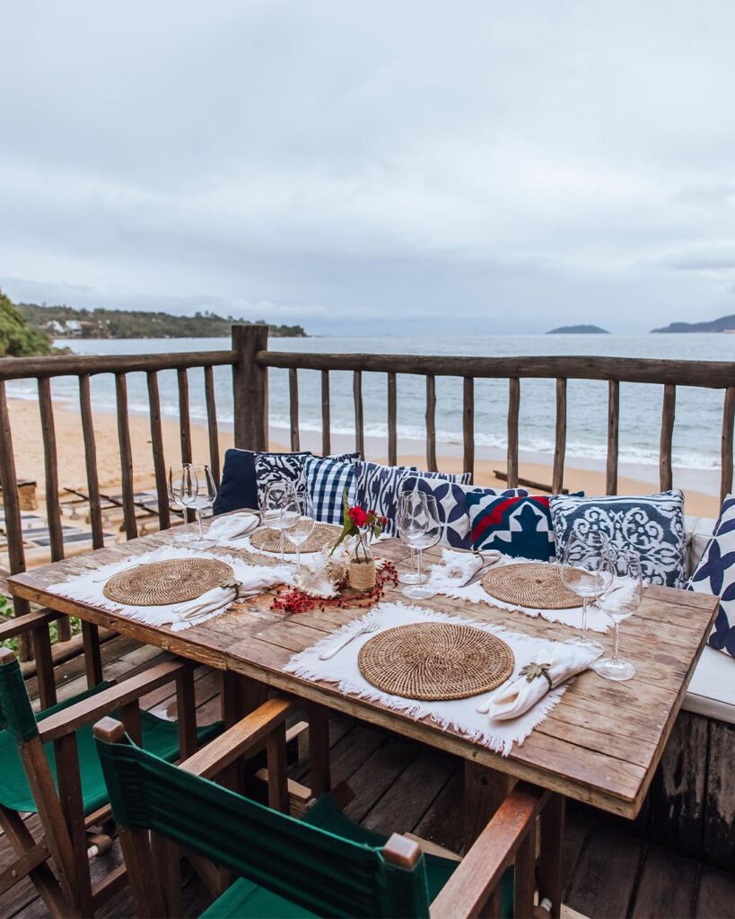 Mesa posta no deck com vista para a praia no TW Guaimbê em Ilhabela. Cenário idílico perfeito entre hotéis românticos em São Paulo para casais.