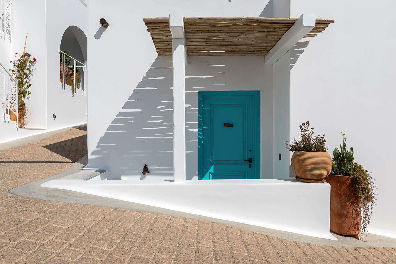 Quarto minimalista com cabeceira em linho e iluminação indireta quente no Nammos Hotel, resort em Mykonos.
