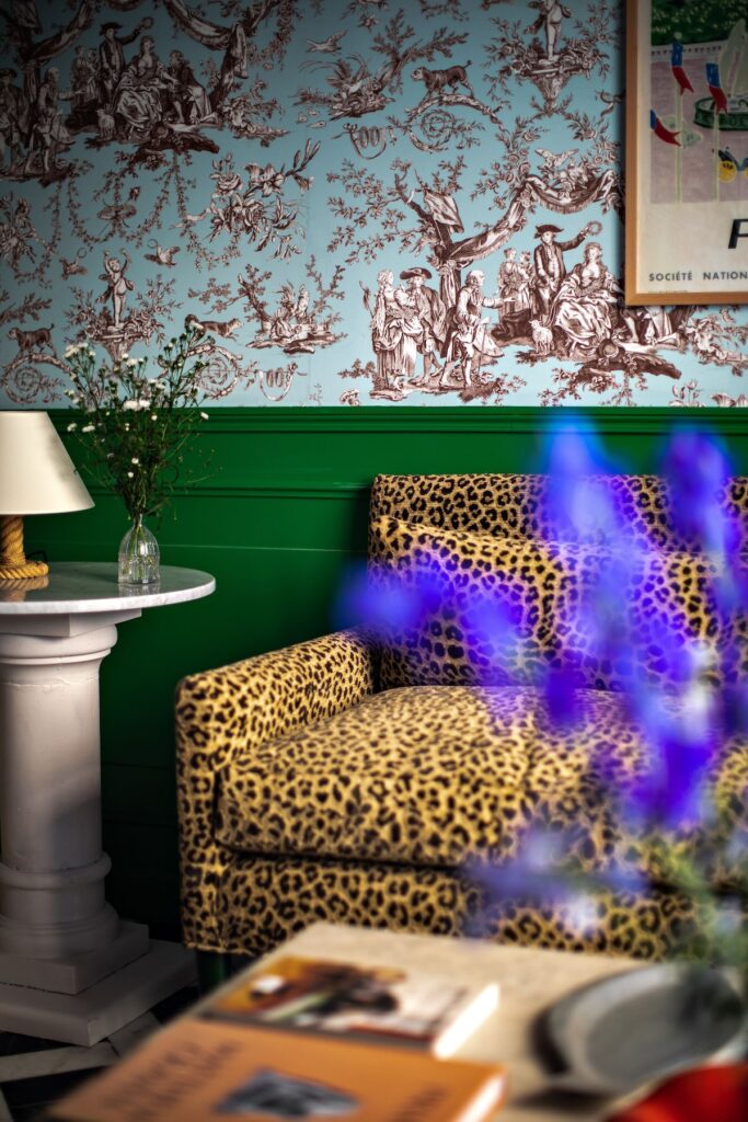 Poltrona com estampa de leopardo e parede Toile de Jouy azul no Hôtel Les Deux Gares, hotel boutique em paris com design maximalista.