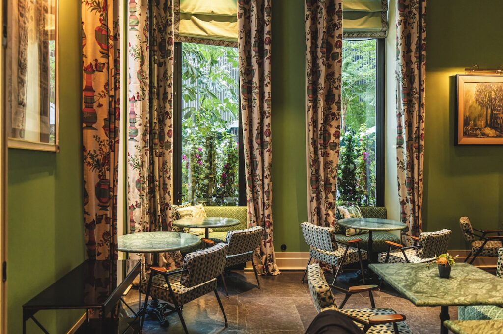 Restaurante Sítio no Valverde Hotel com paredes verdes, mesas de mármore e cadeiras retrô estampadas, design em destaque nos hoteis boutique em lisboa.