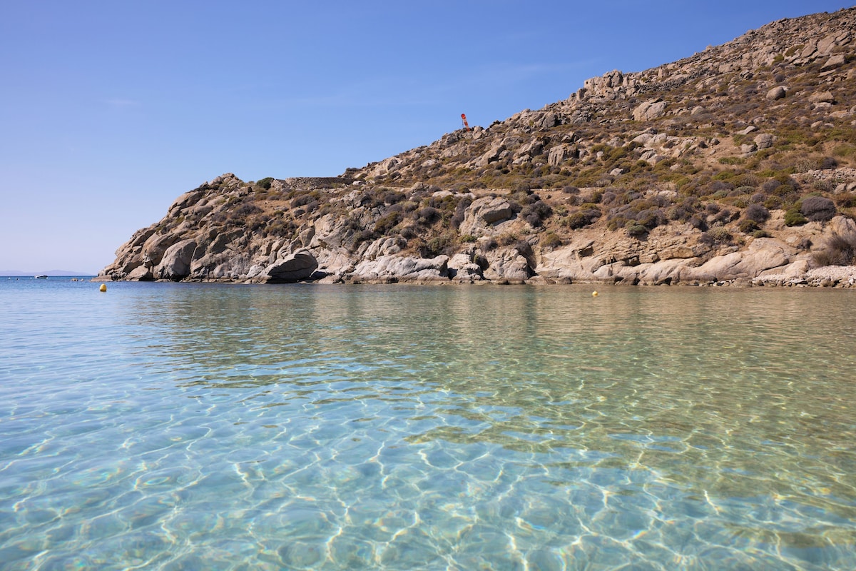 Praia de Psarou com espreguiçadeiras e mar cristalino na frente do Nammos Hotel, badalado resort em Mykonos.