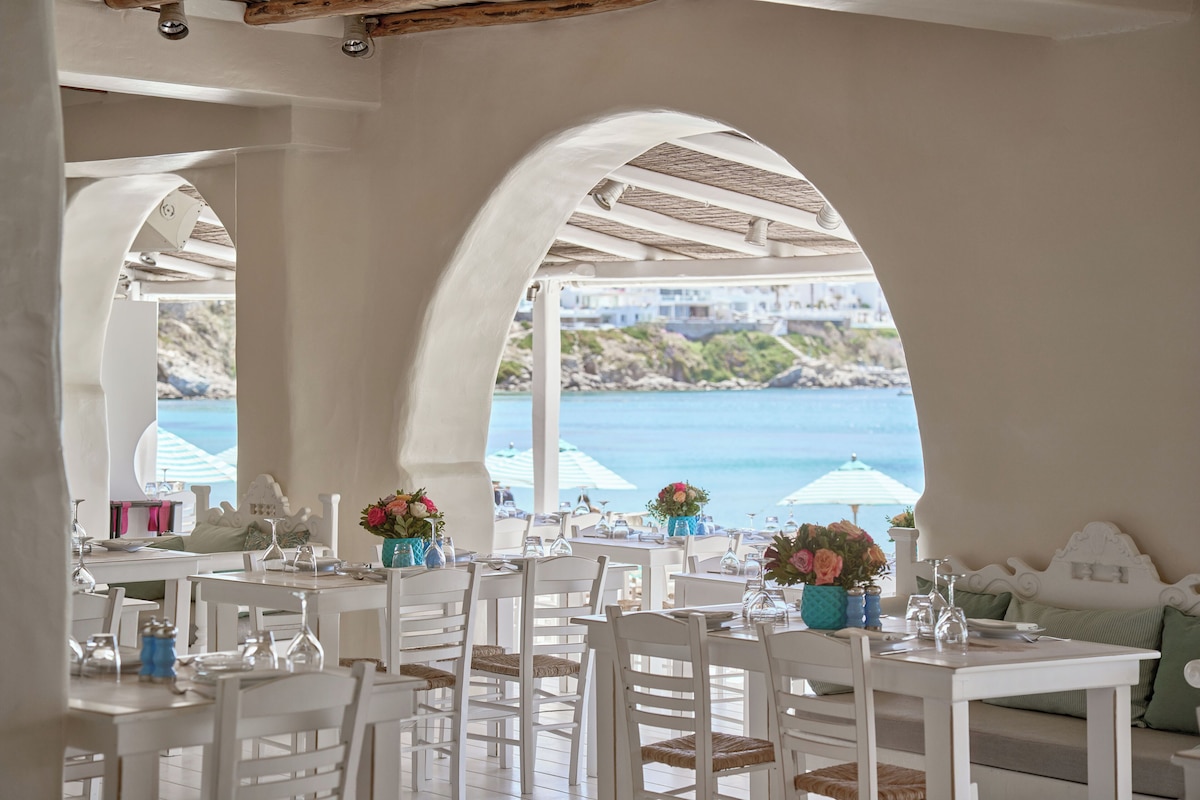 Salão de jantar do NAMMOS Restaurant com arcos gregos e vista para o mar de Psarou no badalado resort em Mykonos.