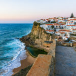 Casario branco de Azenhas do Mar em Sintra sob o crep&uacute;sculo na melhor &eacute;poca para visitar portugal, com piscina natural e praia.