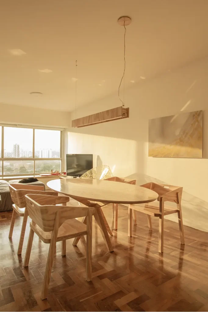 Sala de jantar contemporânea com mesa oval e cadeiras de madeira sob luz dourada de fim de tarde, criando uma decoração aconchegante de inverno.