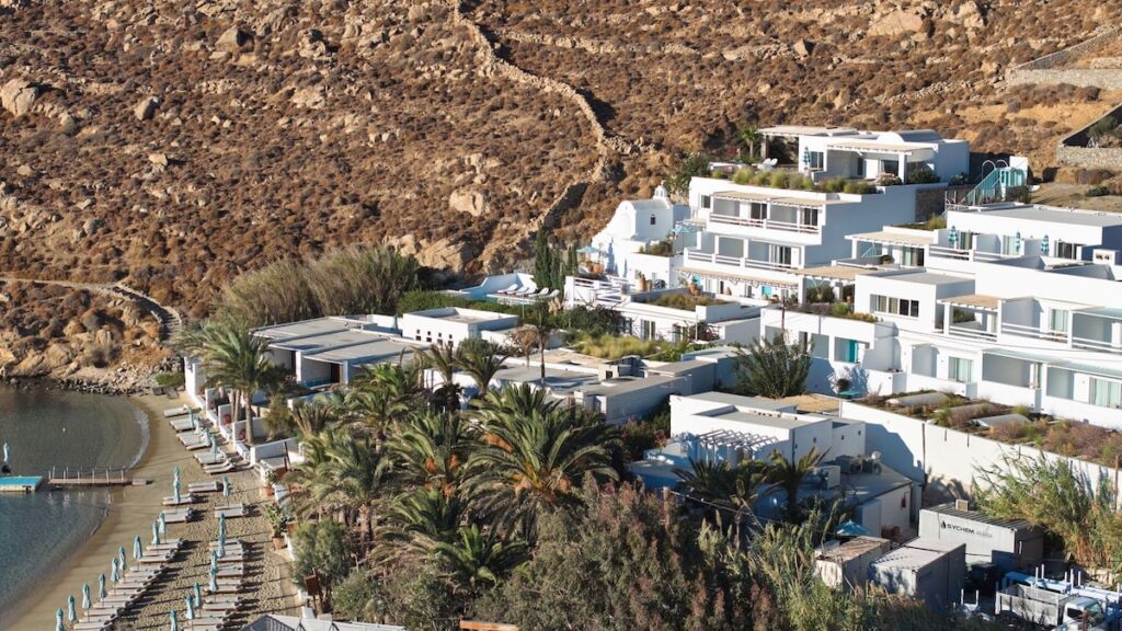 Vista aérea da arquitetura branca e em cascata do Nammos Hotel, um luxuoso resort em Mykonos situado na encosta da praia de Psarou.