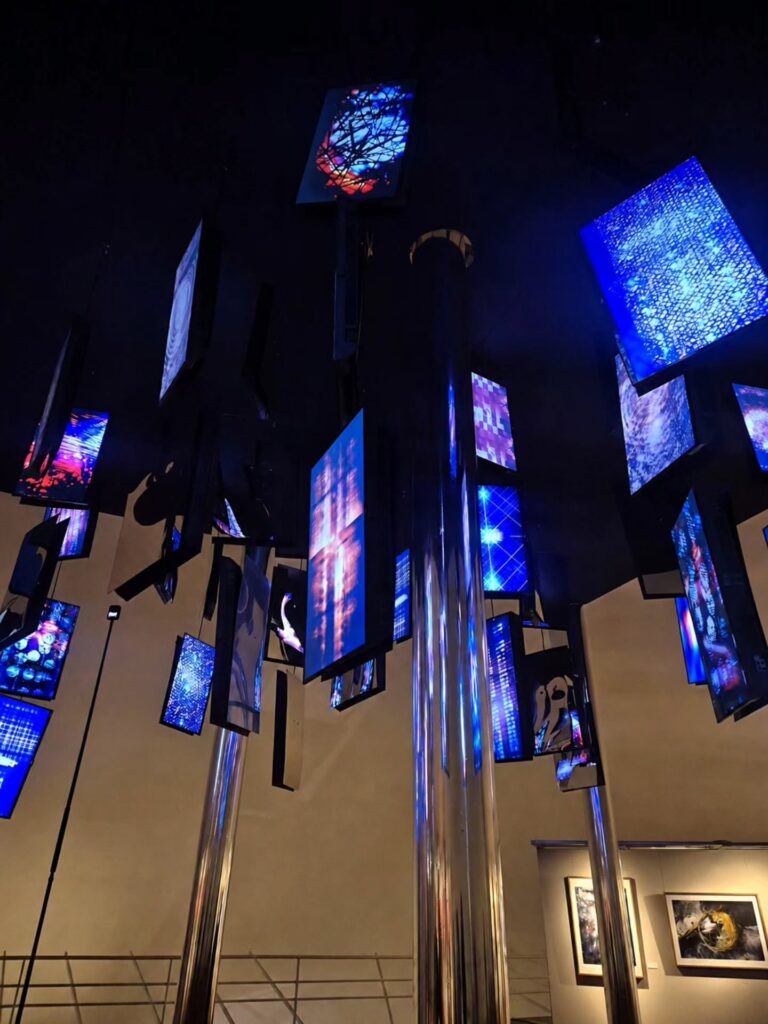 Instalação com pilares cromados e telas de LED suspensas na Oca de Niemeyer, uma das principais exposições em São Paulo de arte e tecnologia.