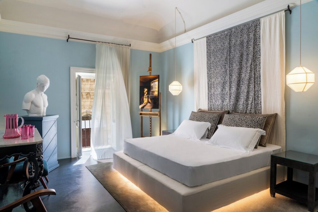 Quarto do Q92 Noto Hotel, que exemplifica o requinte de se hospedar em hotéis boutique na sicilia, com cama flutuante e busto.