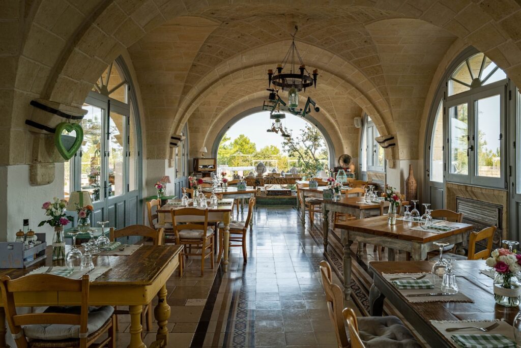 Restaurante abobadado de pedra na Masseria Montenapoleone com mesas de madeira rústica e luz natural.