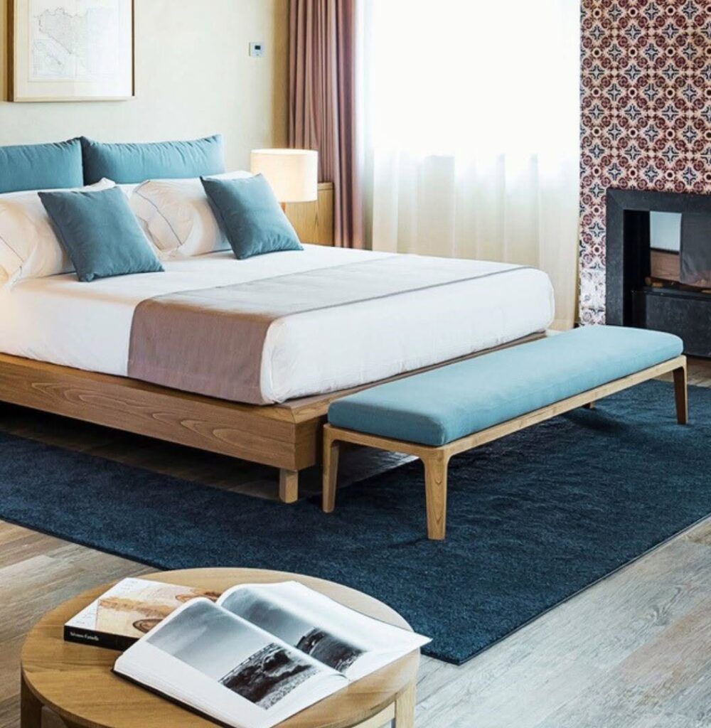 Quarto do Relais San Giuliano, combinando a essência do design com hotéis boutique na sicilia, com cabeceira azul-petróleo.