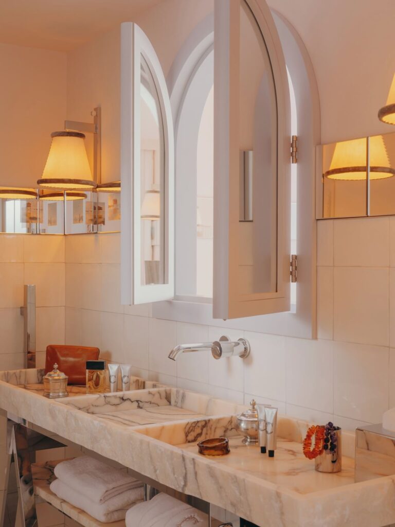 Detalhe do banheiro com bancada de mármore e espelho com arandela no hôtel villa colette, destacando o design de interiores sofisticado.