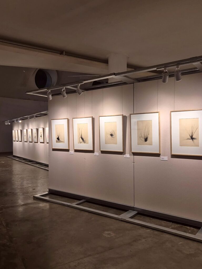Painéis divisórios off-white e quadros minimalistas na Oca, integrando o roteiro de exposições em São Paulo com foco em design e arquitetura.