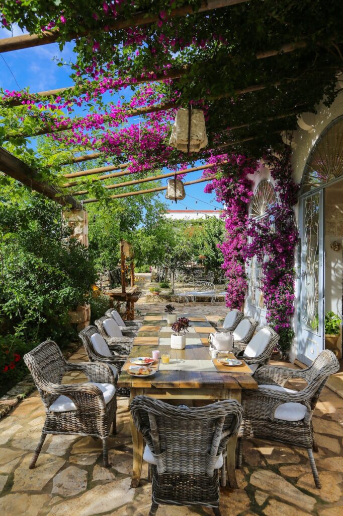 Espaço para café da manhã sob pérgula de madeira e buganvílias na Masseria Montenapoleone.
