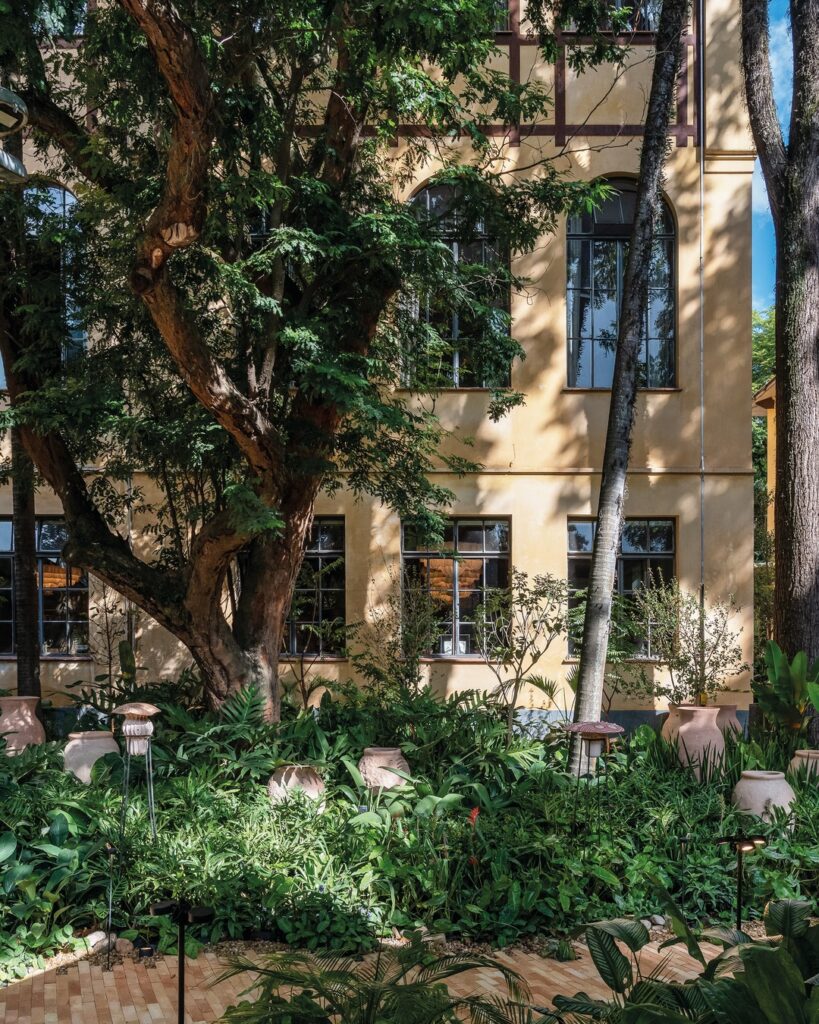 Vasos cerâmicos artesanais e iluminação sob copas de árvores na fachada do espaço Da Terra ao Solo Casacor 2026.