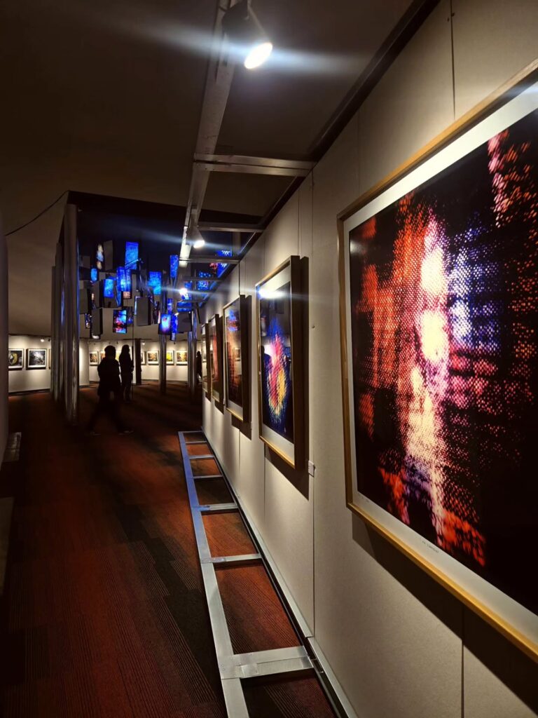 Corredor com iluminação cênica direcionada sobre quadros vibrantes na Oca, integrando as exposições em São Paulo essenciais para designers.